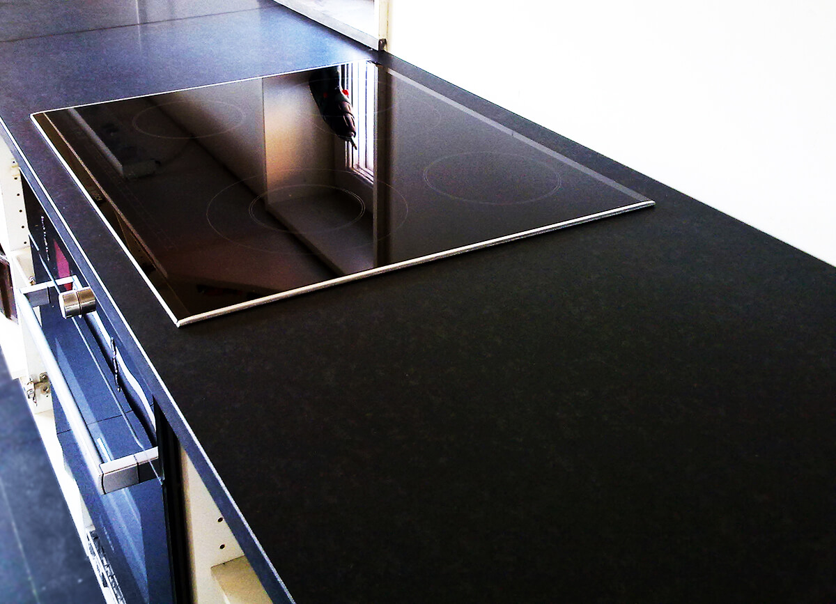 Mat Nero Assoluto-granitbordplade med underlimet vask i dansk køkken